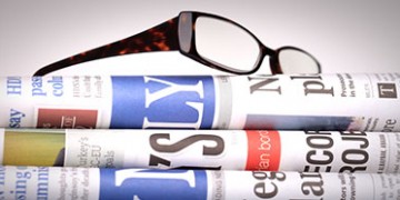 Newspapers staked with eyeglasses on top